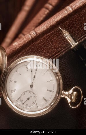 Antique Pocket Watch and Fountain Pen resting on Books Stock Photo