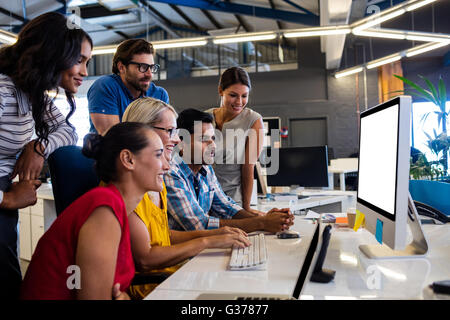 Casual business team working on one computer Stock Photo