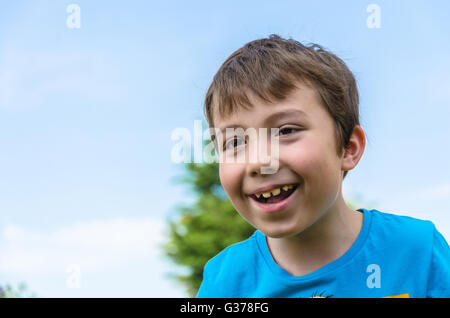 A portrait of a smiling young boy against a blue sky. Stock Photo