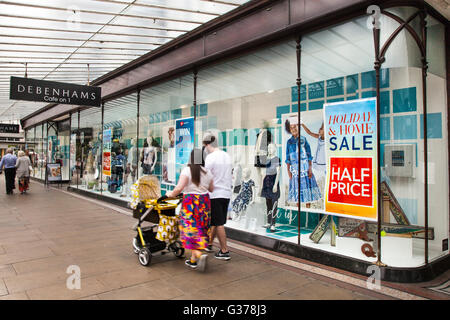 Shoppers & passerby in Lord Street, Southport, Merseyside, UK. People passing Debenhams summer sales and holiday items half price sale. Stock Photo