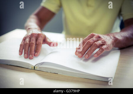 Senior blind man reading a braille book Stock Photo