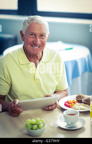 Senior man using digital tablet while having breakfast Stock Photo