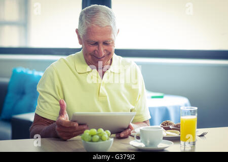 Senior man using digital tablet while having breakfast Stock Photo