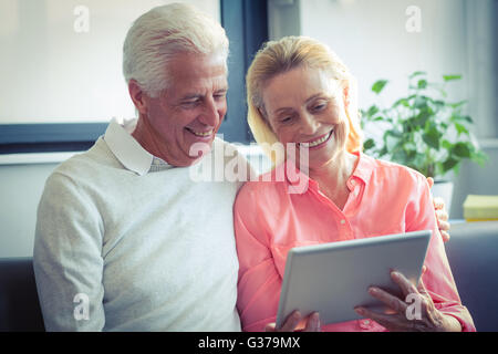 Senior couple smiling while using digital tablet Stock Photo