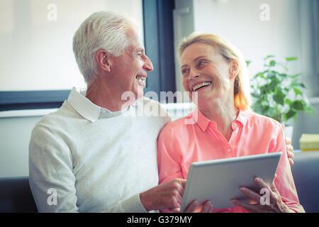 Senior couple smiling while using digital tablet Stock Photo