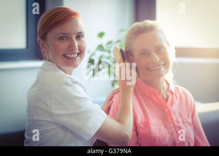 Female nurse combing hair of senior woman Stock Photo