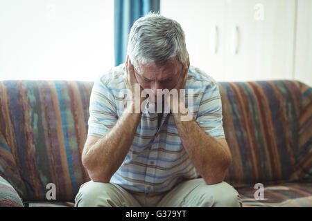 Upset senior man sitting in living room Stock Photo