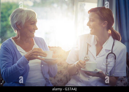 Smiling doctor and patient talking while having tea Stock Photo
