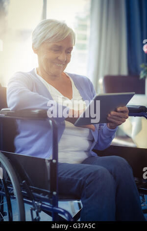 Happy senior woman on wheelchair using digital tablet Stock Photo