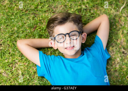 Young boy in spectacle lying on grass Stock Photo
