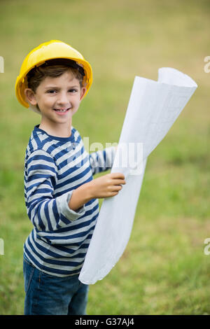 Boy in hard hat holding a plan Stock Photo