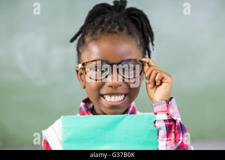 Portrait of happy schoolgirl holding file in classroom Stock Photo