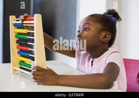 Schoolgirl using a maths abacus in classroom Stock Photo