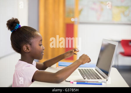 Schoolgirl using laptop in classroom Stock Photo