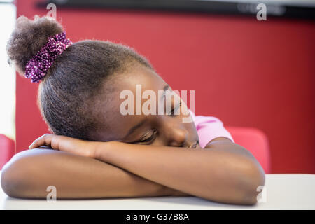 Tired schoolgirl sleeping in classroom Stock Photo