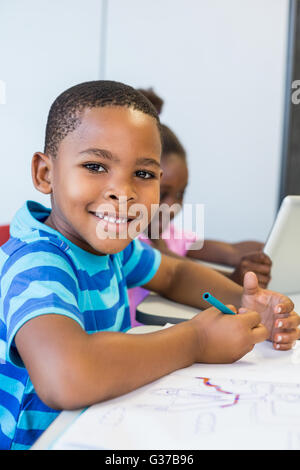 Portrait of schoolboy doing homework in classroom Stock Photo