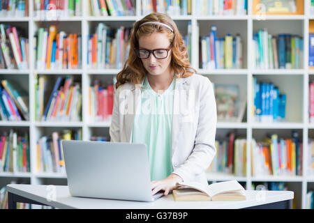 Teacher using laptop in library Stock Photo