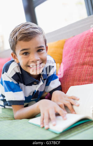 Schoolboy lying on sofa and reading book Stock Photo