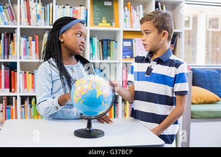 School kids discussing with each other in library with globe on table Stock Photo