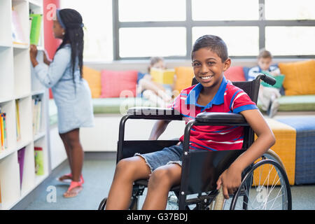 Portrait of disabled schoolboy on wheelchair in library Stock Photo