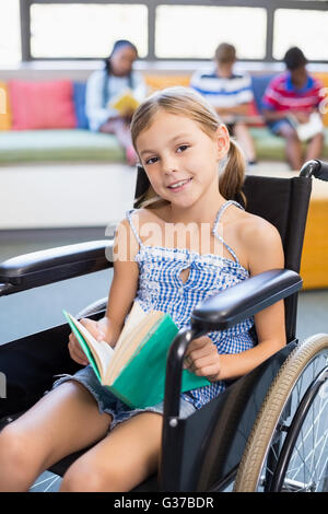 Portrait of disabled school girl reading book in library Stock Photo