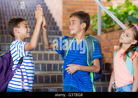 School kids giving high five on staircase Stock Photo