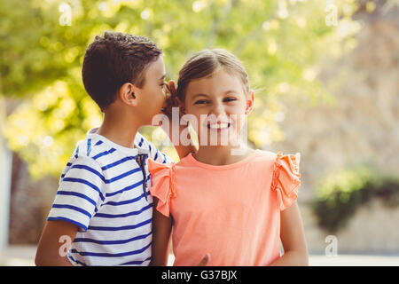 Happy boy whispering a secret in girls ear Stock Photo