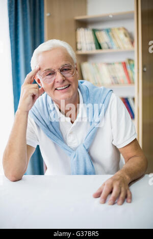 Smiling senior man sitting at table Stock Photo