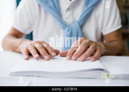 Senior man using braille to read Stock Photo