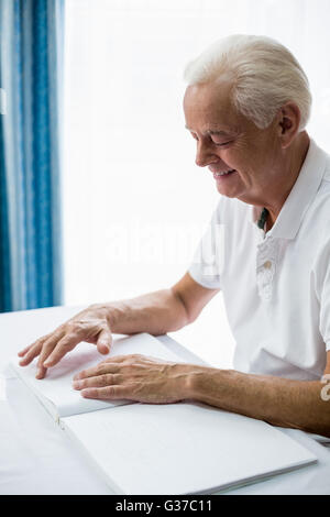 Senior man using braille to read Stock Photo