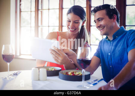 Couple using a digital tablet during lunch Stock Photo