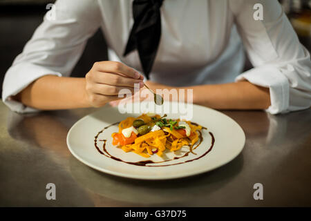Mid section of chef garnishing pasta dish with olive Stock Photo