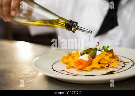 Chef pouring olive oil on meal Stock Photo