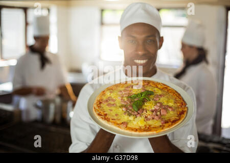 Portrait of smiling chef showing pizza Stock Photo