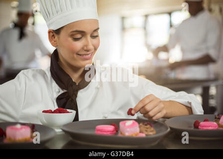 Smiling female chef finishing dessert plates Stock Photo