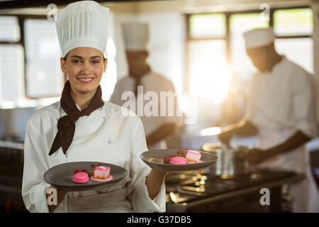 Portrait of smiling female chef presenting dessert plates Stock Photo