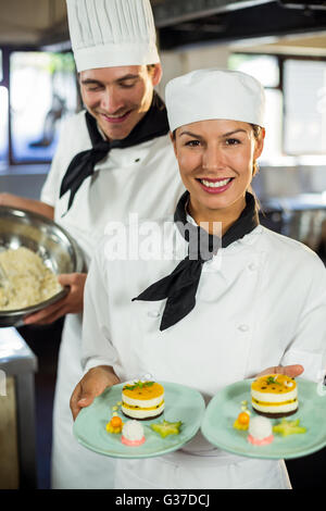 Portrait of female chef presenting dessert plates Stock Photo