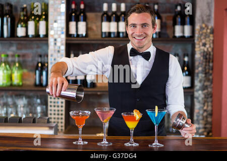 Portrait of bartender pouring a orange martini drink in the glass Stock Photo