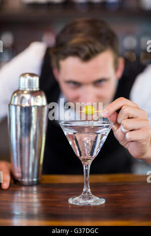 Bartender garnishing cocktail with olive Stock Photo