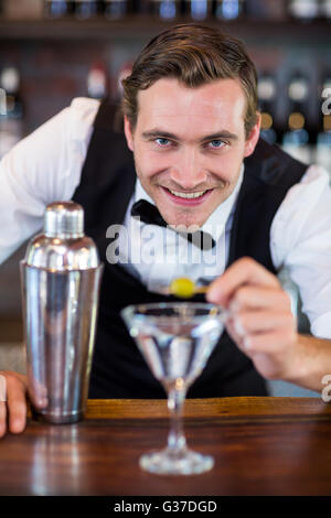 Portrait of bartender garnishing cocktail with olive Stock Photo