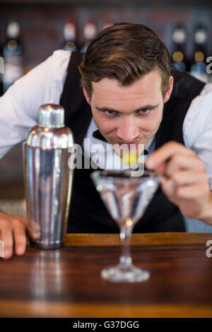 Bartender garnishing cocktail with olive Stock Photo