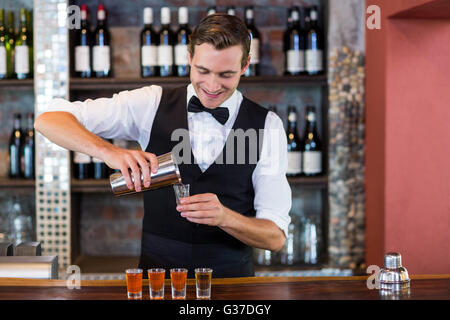 Bartender pouring tequila into shot glasses Stock Photo