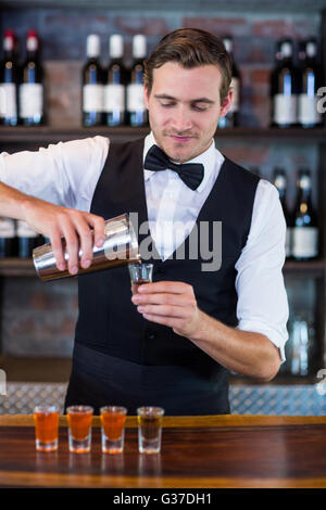 Bartender pouring tequila into shot glasses Stock Photo