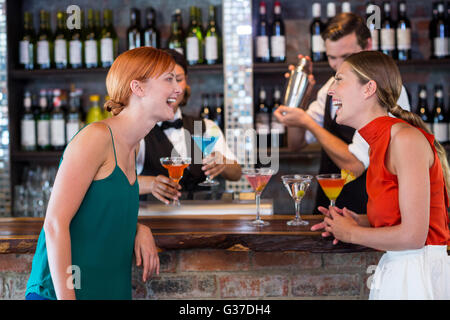 Friends standing at counter while bartender preparing a drink Stock Photo