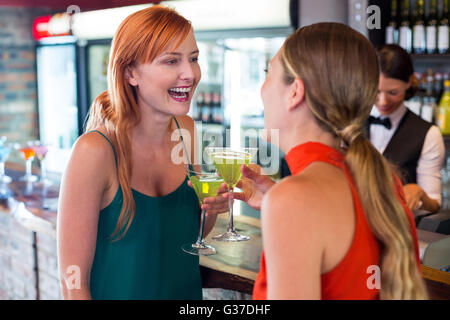 Happy friends holding a cocktail in front of bar counter Stock Photo