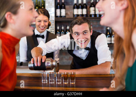 Bartender pouring tequila into shot glasses Stock Photo