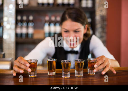 Bartender placing shot glasses on bar counter Stock Photo