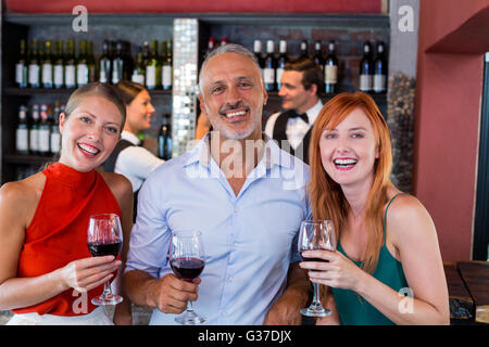 Portrait of friends standing at bar counter with a glass of red wine Stock Photo