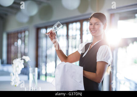 Smiling waitress holding up a empty wine glass Stock Photo