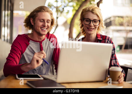 Couple using a laptop on an outdoor terrace Stock Photo